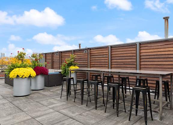 A patio with a table and chairs and flower pots.