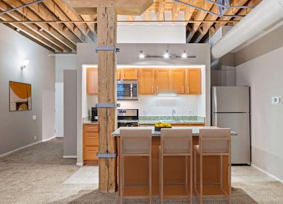 A kitchen with wooden bar stools and a white countertop.