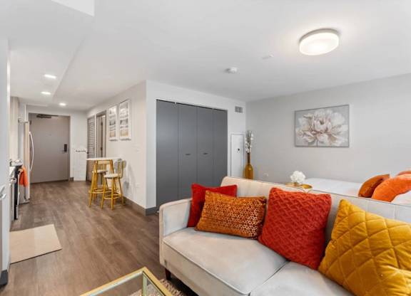 A living room with a white couch and orange pillows.