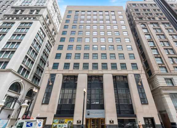 The building in the image is a tall, beige, rectangular structure with a large entrance and a sign that reads "HILLEN".