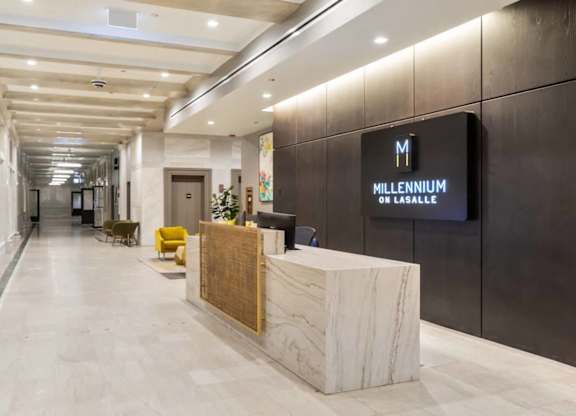 A reception area with a marble counter and a sign that says "Millennium on Lasalle".
