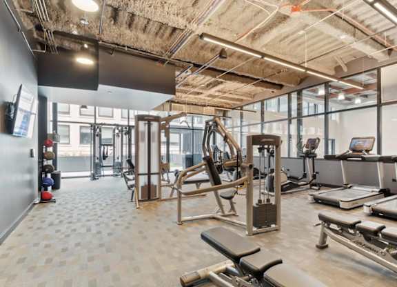 A gym with a variety of equipment including treadmills, weights, and exercise machines.