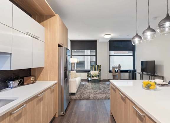 A modern kitchen with a refrigerator, sink, and a dining area with chairs and a table.