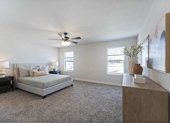 A bedroom with a bed, nightstand, and a ceiling fan.