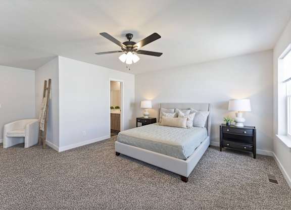 A bedroom with a large bed, a chair, and a ceiling fan.