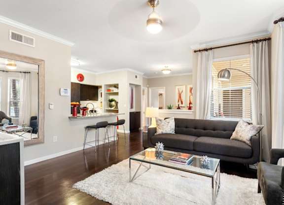 A living room with a grey couch and a glass coffee table.