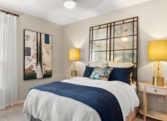 A bedroom with a bed, nightstand, and two lamps.