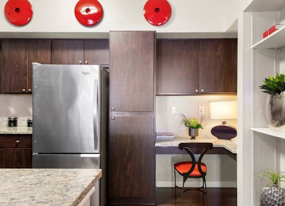 A kitchen with a stainless steel refrigerator and wooden cabinets.
