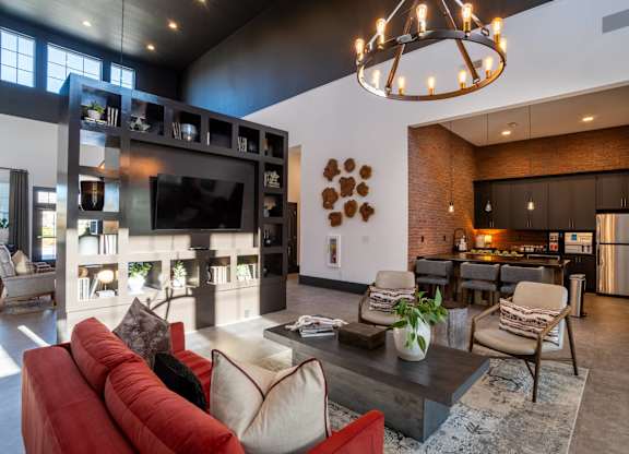 A living room with a red couch and a chandelier.