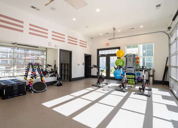 A room with exercise equipment and a large window letting in sunlight.