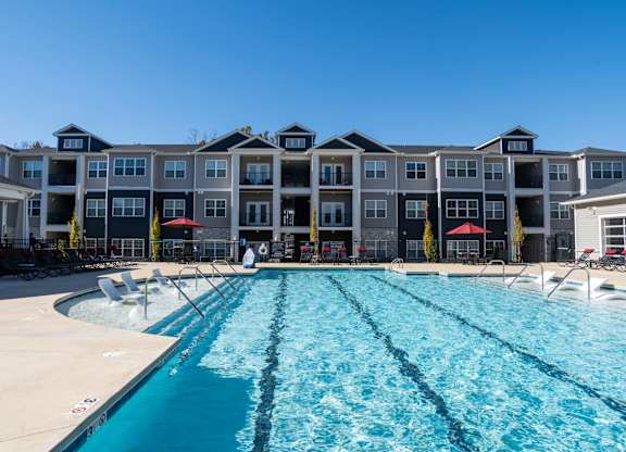 A large swimming pool in front of a multi-story apartment building.