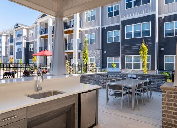 A modern outdoor kitchen area with a table and chairs.