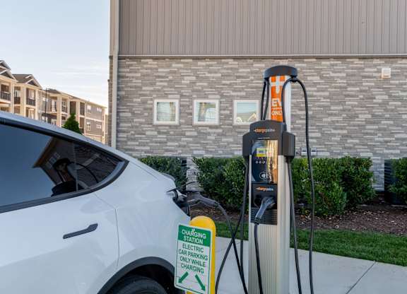 A white car is plugged into an electric car charging station.