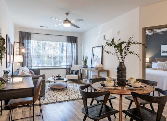 A dining room with a table set for two and a bed in the background.