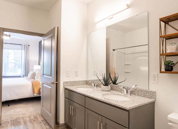 A bathroom with a double sink vanity and a mirror above it.