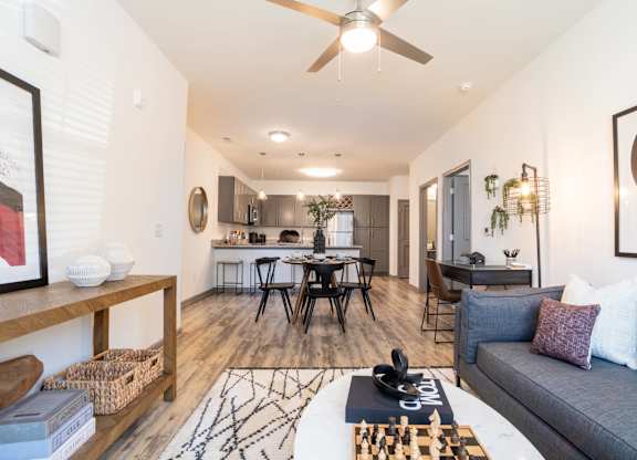 A living room with a grey couch, a coffee table, and a ceiling fan.
