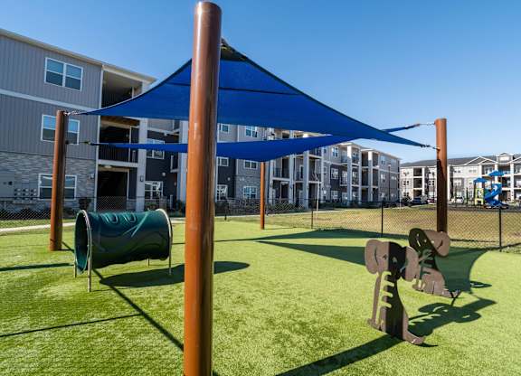 A playground with a blue canopy and a green slide.