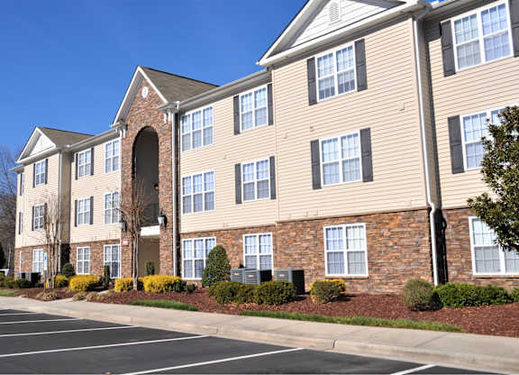 A large apartment building with a parking lot in front.