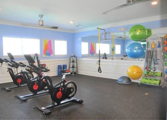 A gym with exercise equipment and a fan.