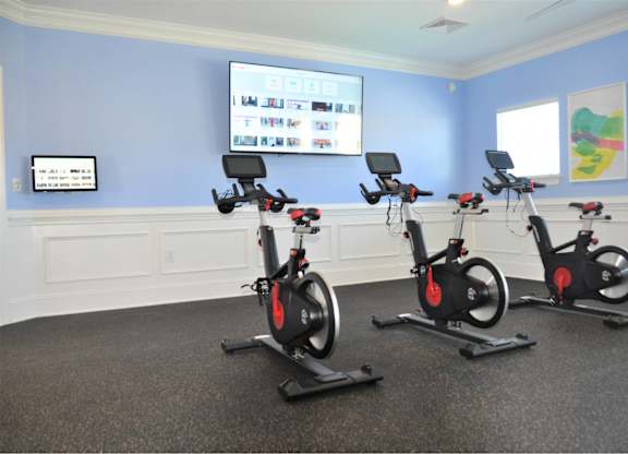 Three stationary bikes are lined up in a room.