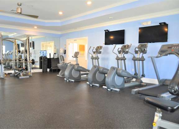A gym with treadmills, weights, and exercise equipment.
