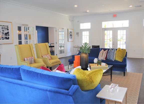 A living room with blue couches and yellow chairs.