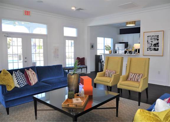 A living room with a blue couch, yellow chairs, and a coffee table.