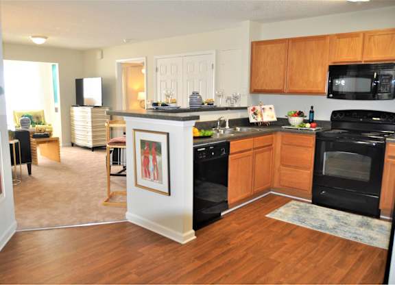 A kitchen with black appliances and wooden cabinets.