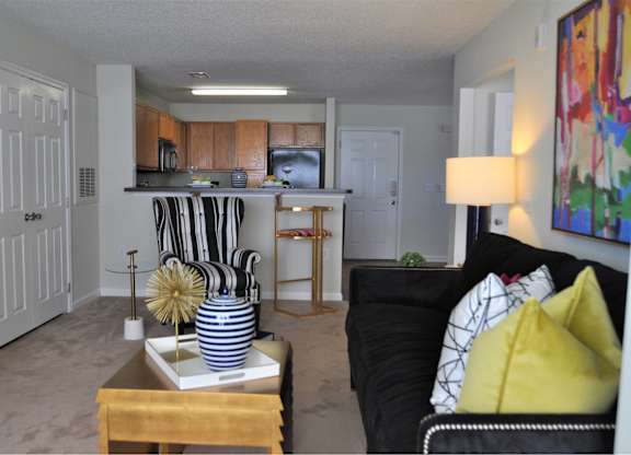 A living room with a black couch and a coffee table with a striped vase on it.
