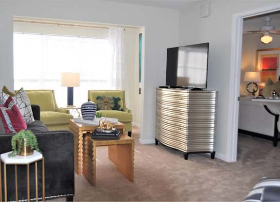 A living room with a black couch, a yellow chair, a wooden coffee table, and a television.