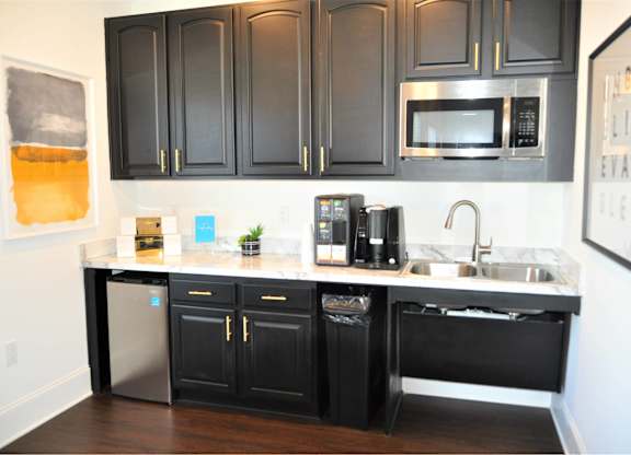 A kitchen with black cabinets and a stainless steel dishwasher.