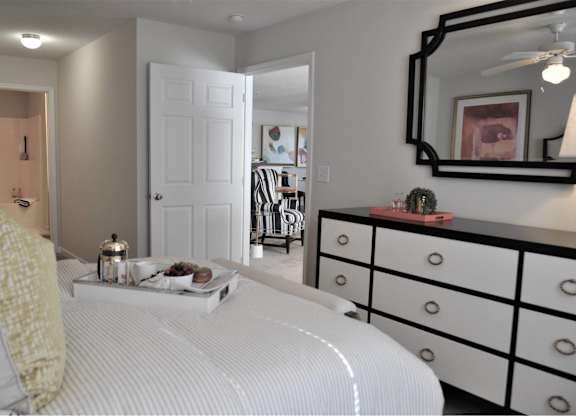 A white bed with a yellow pillow and a tray of food on it.