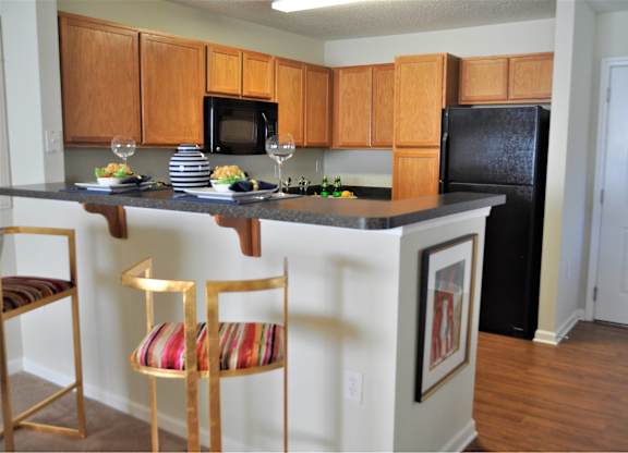A kitchen with a black refrigerator and wooden cabinets.