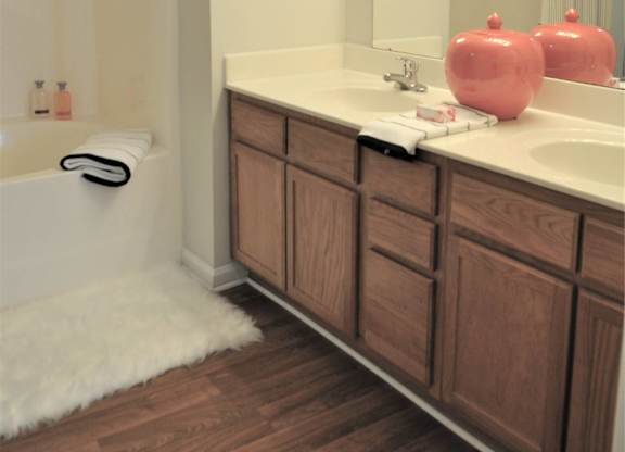 A bathroom with a white tub and a wooden vanity.