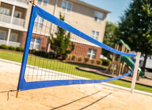 A blue volleyball net is set up on a sandy court.