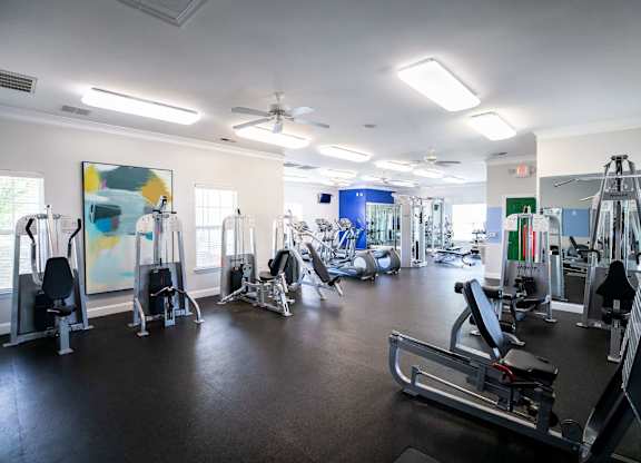 A gym with a variety of equipment including treadmills, weights, and exercise machines.