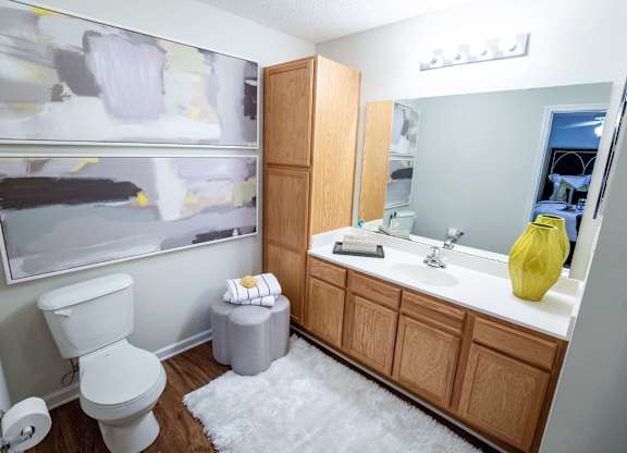A bathroom with a toilet, sink, and a painting on the wall.