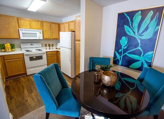 A kitchen with a table and chairs in front of a painting.