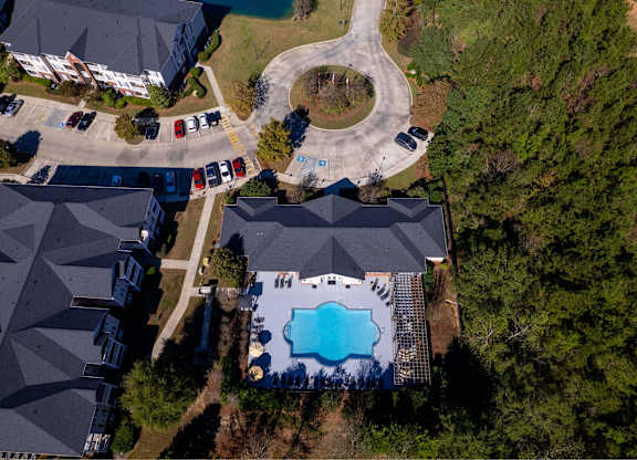 A bird's eye view of a residential area with houses, cars, and a swimming pool.