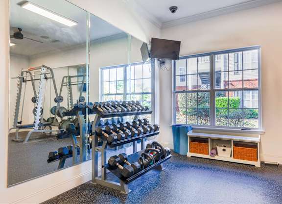 A gym with a mirror, weights, and exercise equipment.