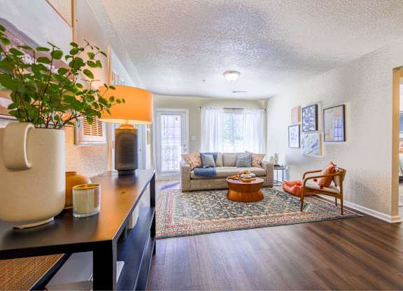 A living room with a couch, a chair, a potted plant, and pictures on the wall.