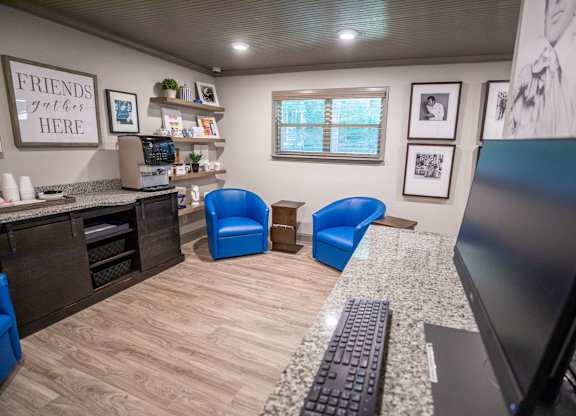 A room with a desk, chairs, and a computer.