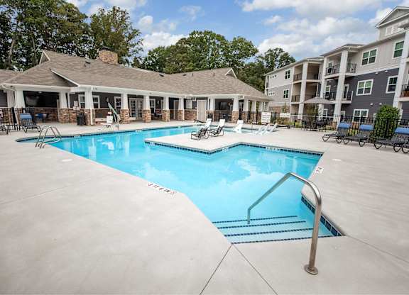 A large swimming pool with a diving board in the middle of a patio area.