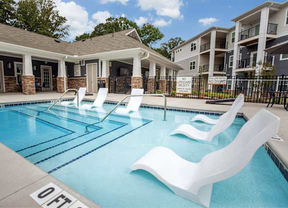 A pool with white chairs and a sign that says
