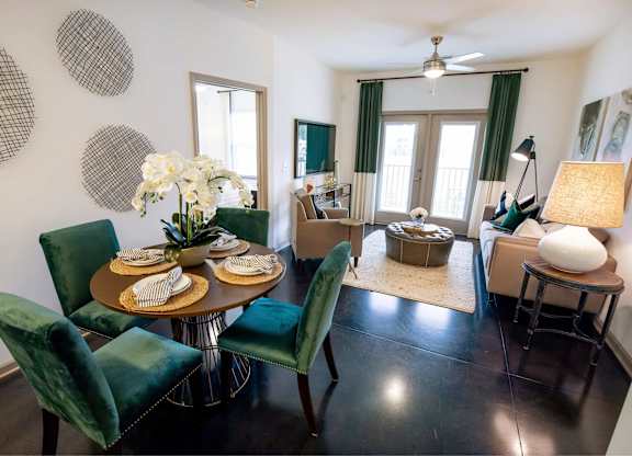 A dining room with a table set for two and green chairs.