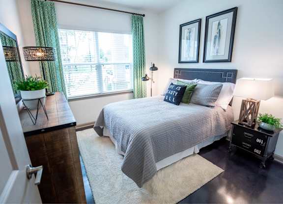 A bedroom with a bed, nightstands, and a window with green curtains.