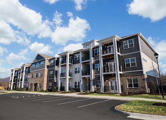 A large apartment complex with a parking lot in front.