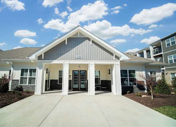 A modern house with a large front porch and a driveway.