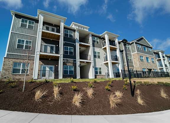 A modern apartment building with a landscaped front yard.