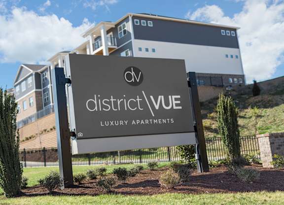 A sign for District Vue Luxury Apartments in front of a building.